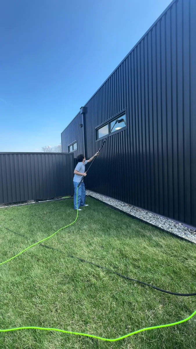 Commercial window cleaning with a water-fed pole on a metal building