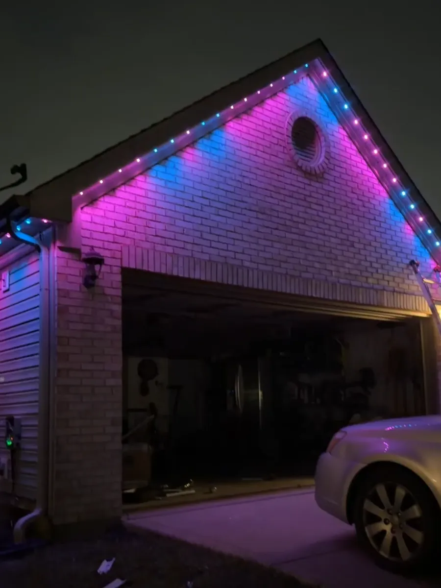 Permanent LED lights in pink and blue on a brick garage gable at night