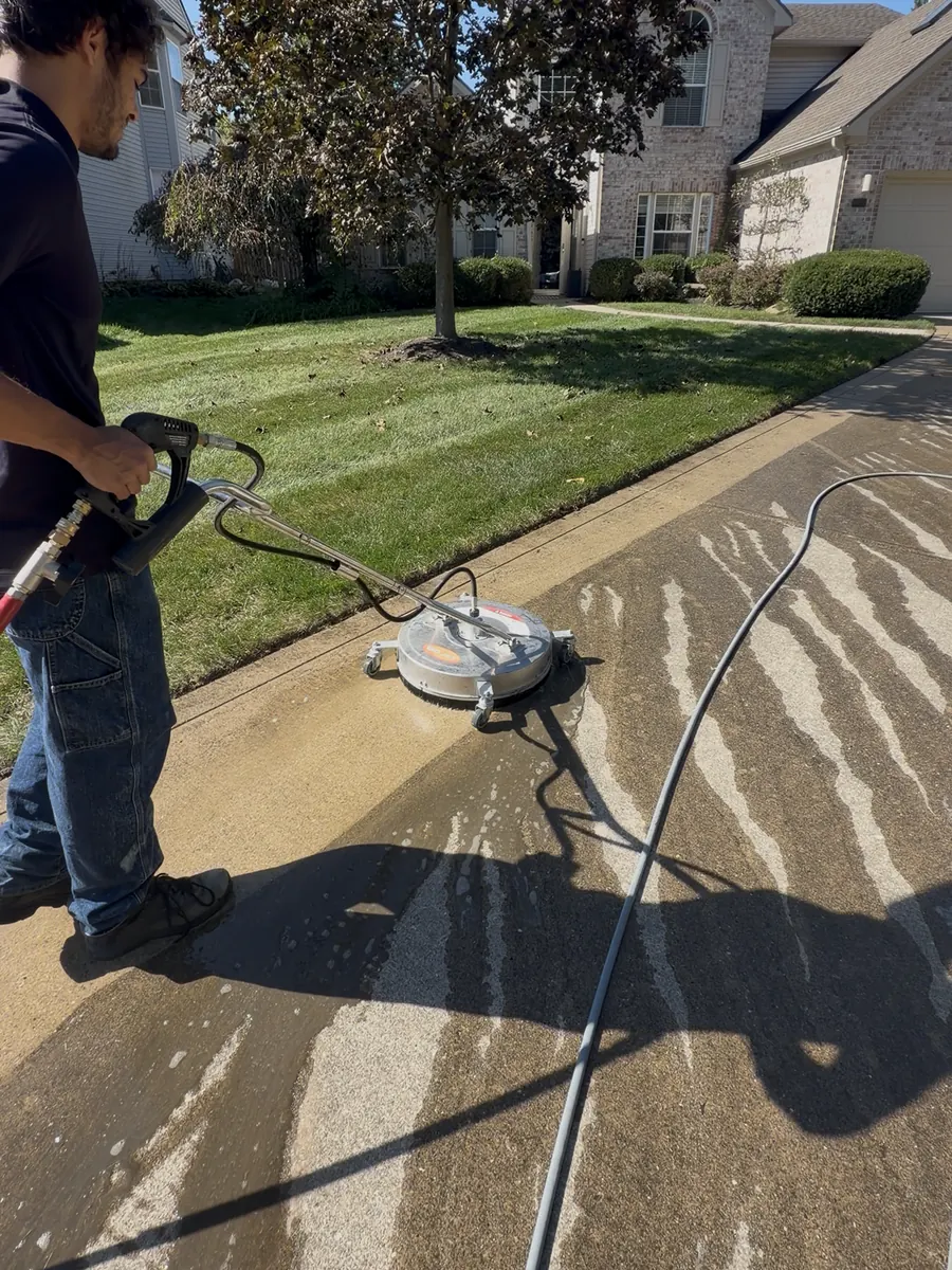 Lakeline technician pressure washing a concrete driveway with a surface cleaner